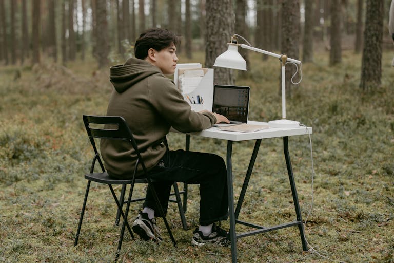 A person at a minimalist desk, working on a laptop with no notifications, surrounded by greenery or natural light.