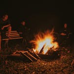 A peaceful night sky with someone sitting calmly by a campfire.