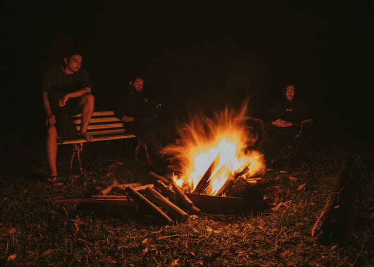 A peaceful night sky with someone sitting calmly by a campfire.