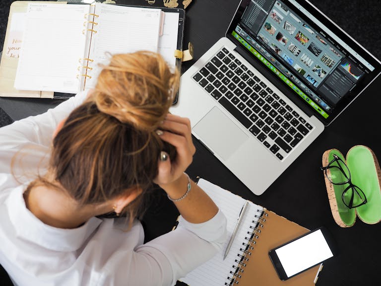 A person juggling too many tasks with a stressed expression, surrounded by