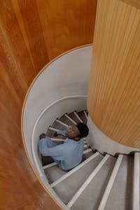 A person looking at a staircase leading upward, symbolizing growth and progression, with light shining from the top.