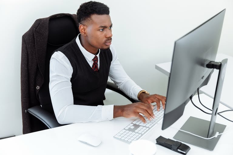 A person working intensely at a desk surrounded by minimal distractions.