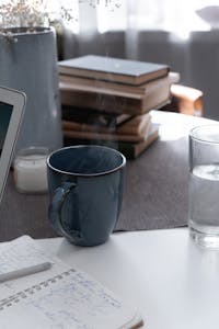 Sunrise light hitting a calm desk with a laptop, notepad, and cup of tea.