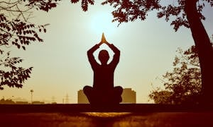 A person meditating outdoors with their phone turned off beside them