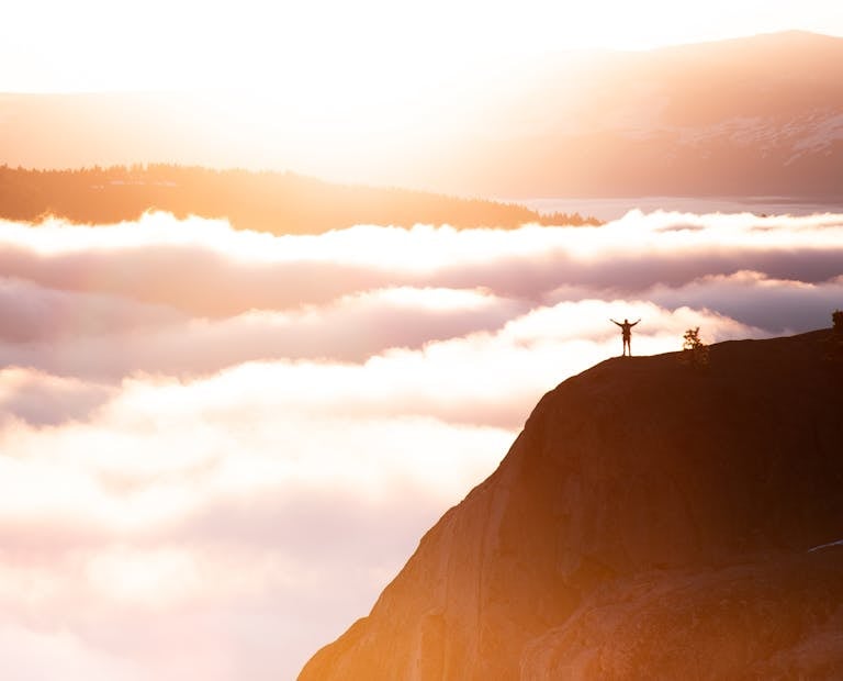 person climbing a mountain hidden in clouds, only the feet and steps visible, not the peak.