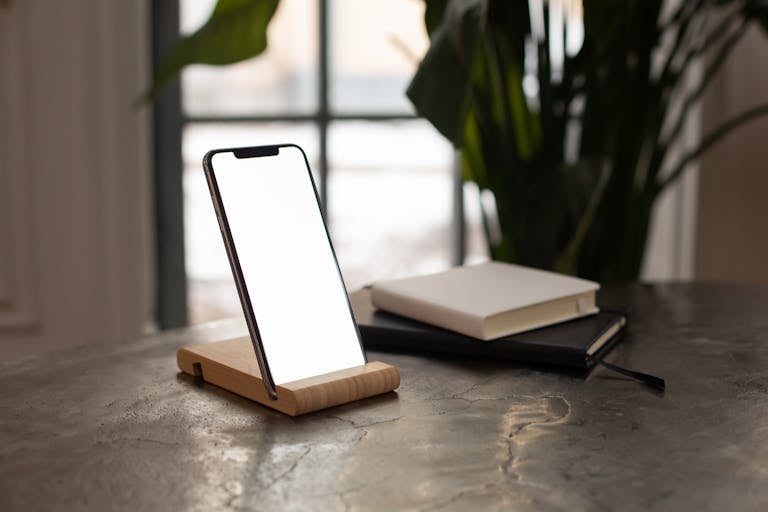 A peaceful workspace with a phone turned off, a journal, and a plant.