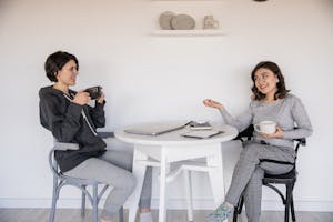 Someone putting their phone face-down next to a coffee mug, smiling and chatting with friends.