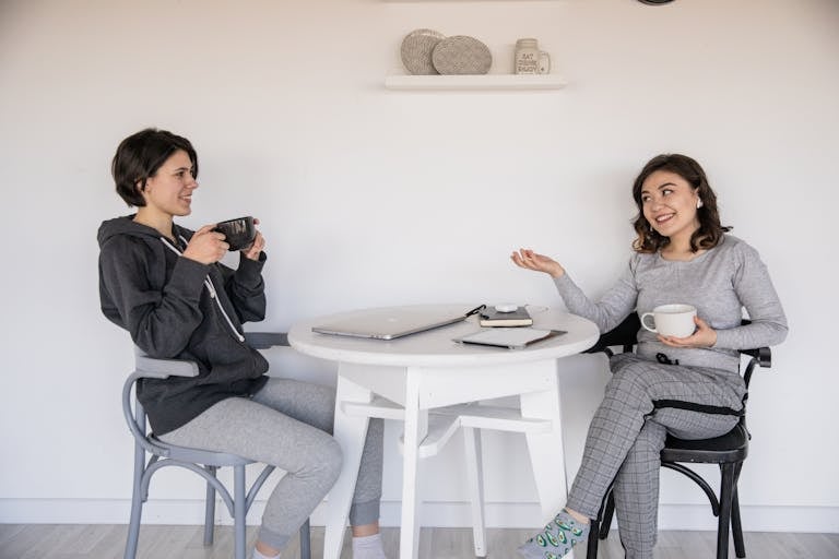 Someone putting their phone face-down next to a coffee mug, smiling and chatting with friends.