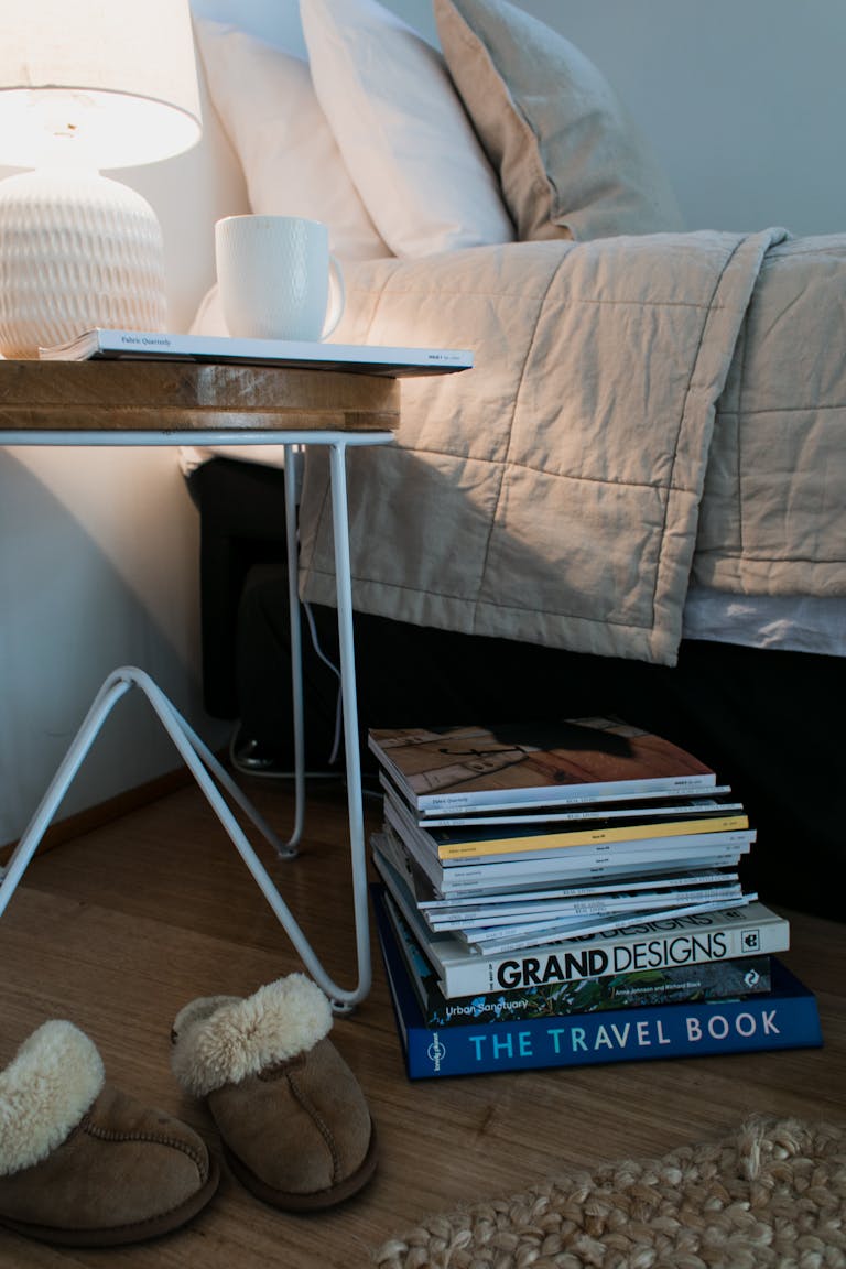 A calm bedroom scene with soft lighting, a journal, and a cup of tea on a nightstand.
