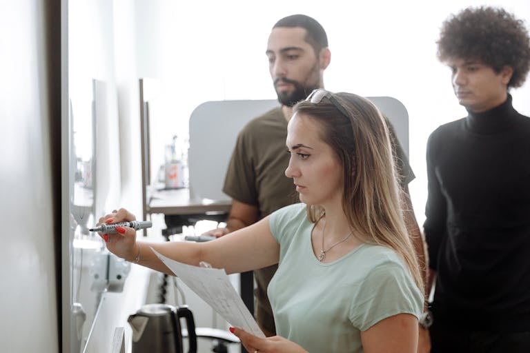 A team actively brainstorming around a whiteboard filled with colorful notes and diagrams.