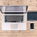 Idea: A minimalist workspace with a laptop, notebook, and a turned-off phone in the corner.