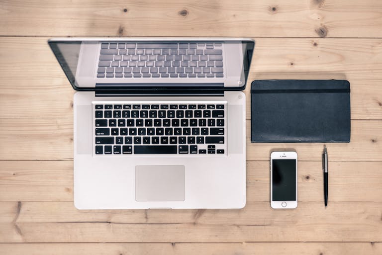 Idea: A minimalist workspace with a laptop, notebook, and a turned-off phone in the corner.