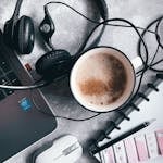 A digital notepad open on a tablet beside a calming cup of tea and headphones.
