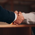 A professional networking event or two individuals shaking hands in a business setting.