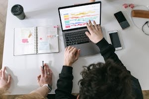 A person working at a desk with a phone turned off and only a laptop, illustrating digital focus.