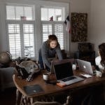 A person working on their side hustle at a desk, with a laptop, notepad, and a cup of coffee next to them.