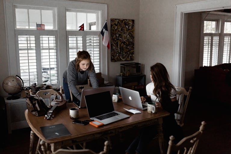 A person working on their side hustle at a desk, with a laptop, notepad, and a cup of coffee next to them.
