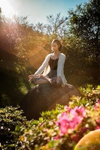 A person meditating in nature with their phone turned off beside them.