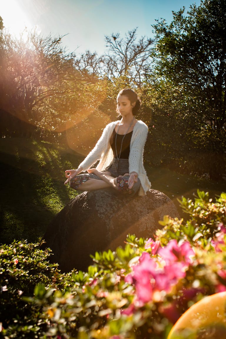A person meditating in nature with their phone turned off beside them.