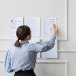 Woman organizing wall planner in office showing strategy and planning.