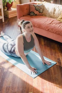 Woman practicing yoga in a bright room, enjoying a morning stretch on a yoga mat.