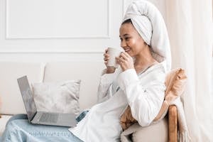 A person relaxing with a coffee while their laptop shows completed tasks