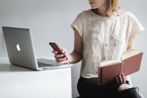 A person turning off phone notifications while working at a desk with minimal digital clutter