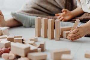 A hand placing a small domino that leads to progressively larger dominos — symbolizing micro actions leading to big results.