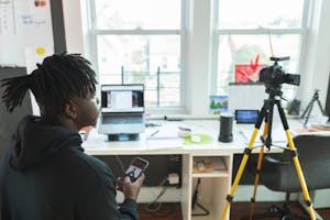 A person working from home with a laptop, surrounded by modern technology, including a comfortable workspace, video conferencing equipment, and digital collaboration tools.