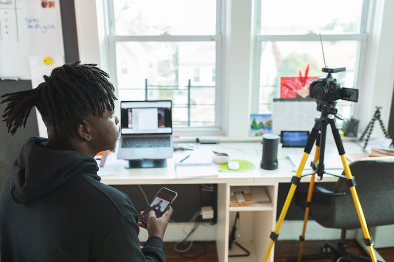 A person working from home with a laptop, surrounded by modern technology, including a comfortable workspace, video conferencing equipment, and digital collaboration tools.