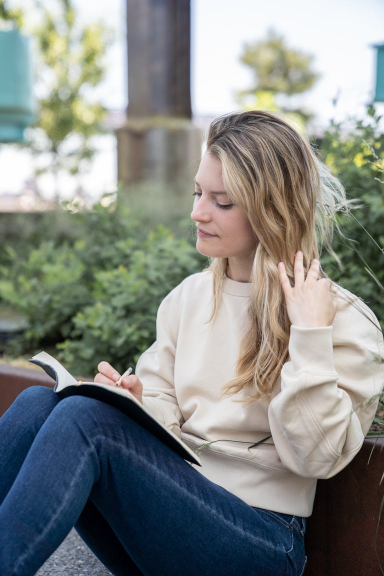 A person sitting in a calm environment with a notebook, planning their digital detox, or meditating in nature